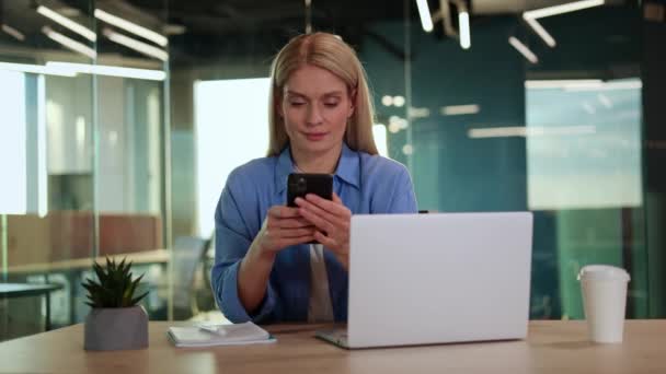 Beztroska Kobieta Niebieskiej Koszuli Patrząc Ekran Smartfona Zębaty Uśmiech Siedząc — Wideo stockowe