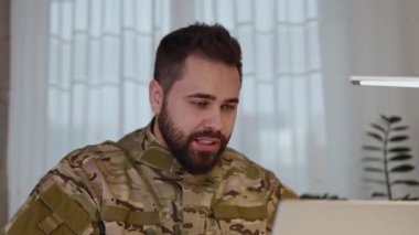 Askeri üniformalı Hava Kuvvetleri mensubu modern dizüstü bilgisayarla online konuşma yapıyor. Beyaz erkek, iş arkadaşlarıyla yapılacak iş planlarını tartışırken web kamerası ile modern cihazlar kullanıyor..