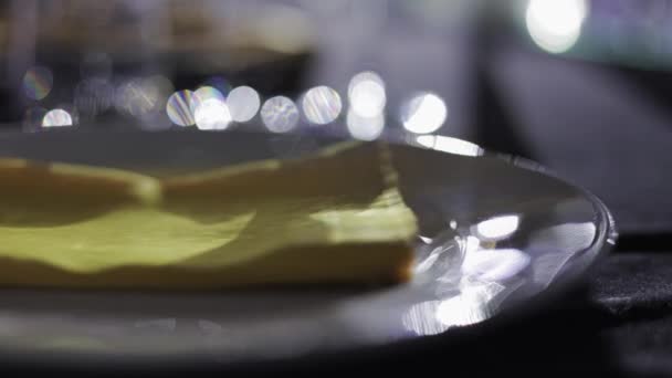 黄色い織物のティッシュはぼやけた背景に黒いテーブルクロスに立っている光沢のある磁器のプラッターを滑らせます カラフルなナプキンを取り 料理を待っている結婚式のゲスト — ストック動画