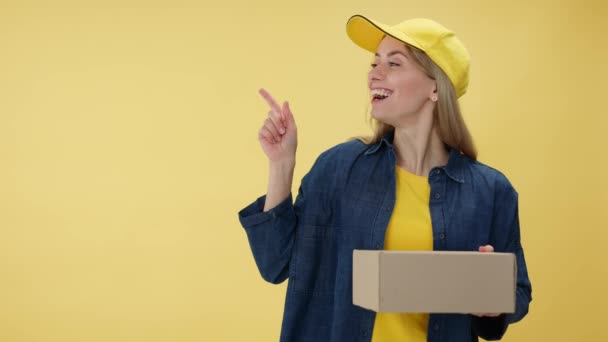 Lachende Vrouwelijke Koerier Cap Holding Box Wijzend Kopieerruimte Met Vinger — Stockvideo