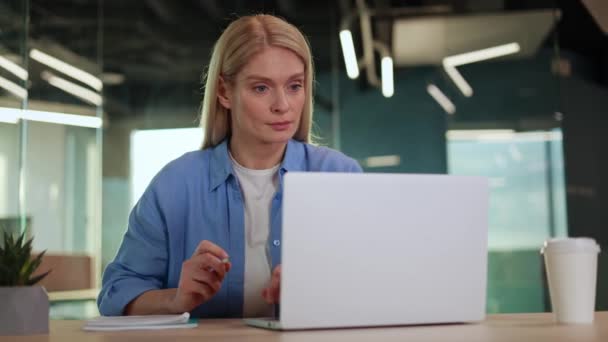 Mujer Rubia Concentrada Usando Computadora Portátil Bloc Notas Mientras Está — Vídeos de Stock