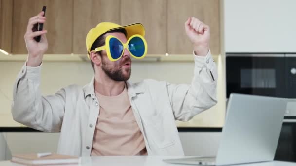 Καυκάσιος Άνδρας Αστεία Γυαλιά Και Κίτρινη Κόμμωση Που Κρατάει Smartphone — Αρχείο Βίντεο
