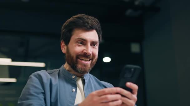Masculino Animado Comemorando Vitória Com Braço Levantado Enquanto Segurando Smartphone — Vídeo de Stock