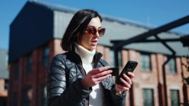 Stresli kadın banka kartı ve akıllı telefonu elinde tutarken başını sallıyor ve dışarıda hayır diyor. Şok olmuş, kısa saçlı bir kadın internette dolandırıcılık yapıyor ve tüm finansmanı kaybediyor..