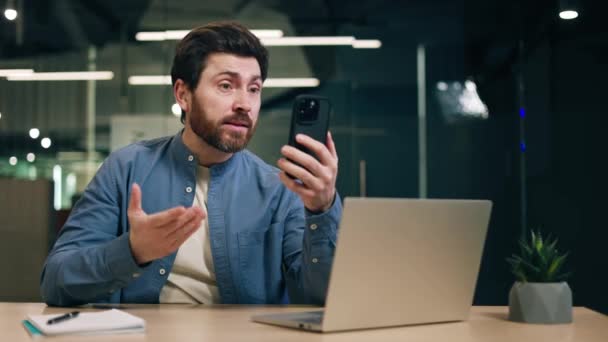 Empleado Masculino Sosteniendo Teléfono Moderno Mientras Habla Hace Gestos Expresivos — Vídeo de stock
