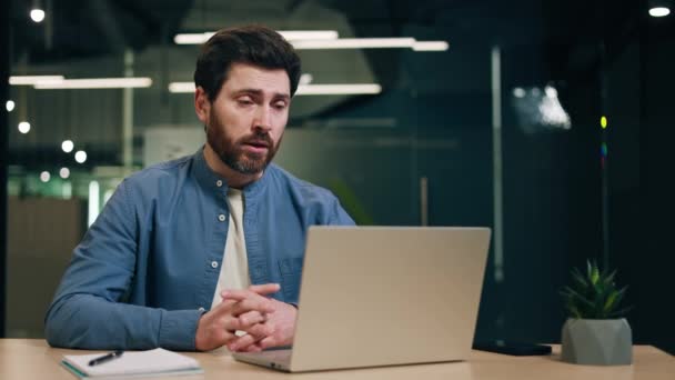 全神贯注的男人穿着蓝色衬衫坐在笔记本电脑前 在网上视频会议上聊天 男性人力资源管理人员面试职位候选人并解释工作详情 — 图库视频影像