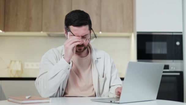 공간에서 노트북으로 작업하는 안경을 문지르는 캐주얼 스타일의 남자를 과부하 화면을 — 비디오