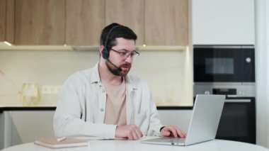 Becerikli erkek serbest yazar ev ortamında müşteriyle uzaktan konuşma yapıyor. Beyaz sakallı adam telsiz kulaklık ve taşınabilir dizüstü bilgisayar kullanarak iletişimi sağlıyor. Mesafe çalışması kavramı.