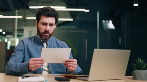 Konzentrierte Männliche Manager Lesen Notizen Während Sie Arbeitsplatz Mit Laptop — Stockvideo