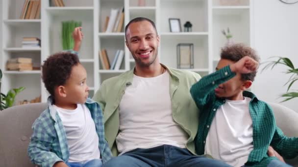 Dois Meninos Multiculturais Abraçando Pai Feliz Enquanto Descansa Sofá Confortável — Vídeo de Stock