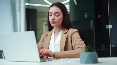 Kabinede kablosuz bilgisayarla çalışan aşırı yorgun Kafkas iş kadınının ön görüntüsü. Resmi takım elbise giymiş yorgun bir kadın. Ofis sandalyesinde otururken sırt ağrısı çekiyor..