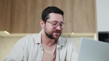 Ev ortamındaki kablosuz bilgisayardaki verimli online toplantının sonunda neşeli erkek kahkahalarına dikkat edin. Gülümseyen adam iş arkadaşlarıyla konuştuktan sonra mutlu hissediyor..