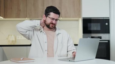 Aşırı çalışan programcı hafif iç mutfağındaki bilgisayar klavyesinde yazarken boynunda ve omzunda gerginlik ve kramplar hissediyor. Yorgun adam evden çalışıyor ve ofis sendromuyla boğuşuyor..