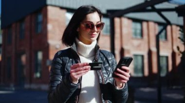 Kendine güvenen bir kadının portresi modern cihazlardan ve bankamatik kartlarından kameraya bakıyor. Gözlüklü gülümseyen bayan banka hesabını telefon numarasına bağlayan kullanıcı deneyiminden memnun..