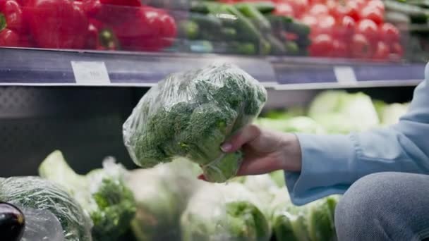 Händerna Kaukasisk Kvinna Som Håller Plastinsvept Broccoli Mataffären Bakgrund Hyllor — Stockvideo