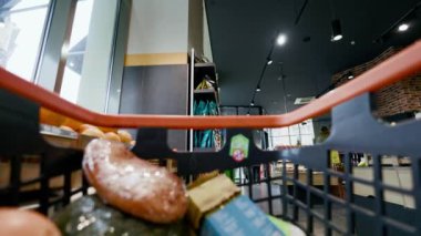 Market arabasının içinde hipermarketin koridorlarında itilme ve taze mallarla doldurulma görüntüsüne yakından bakın. Bilinmeyen bir beyaz, portakal, limon ve muzu arabaya yerleştiriyor..