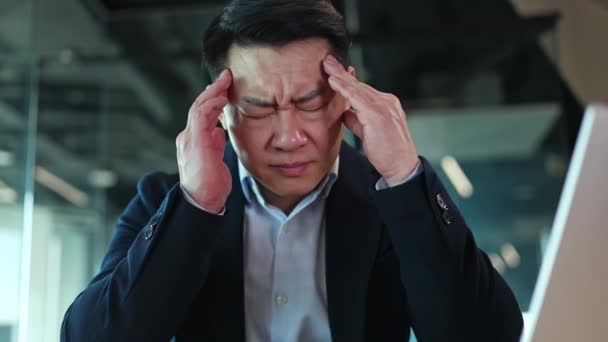 亚洲男性穿着经典西服 双手按摩太阳穴 同时感到剧烈头痛 因工作压力而出现不愉快症状的精疲力竭的办公室职员 — 图库视频影像