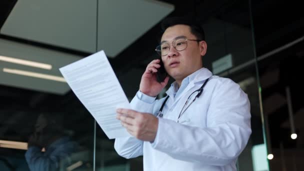 Profesjonalny Medyk Białej Szacie Stetoskopem Trzymający Papiery Rozmawiający Przez Telefon — Wideo stockowe