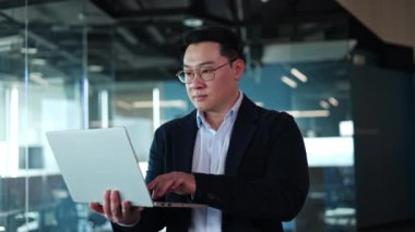 Tek elle yazarken şık giyinen zeki bir adam dizüstü bilgisayar giyer. İş arkadaşlarıyla iletişim kurmak ve internetteki bilgilere erişmek için dijital aygıt kullanan başarılı yönetici.