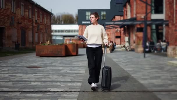 Confident Caucasian Female Walking Paved Path Pulling Black Rolling Suitcase — Stock Video