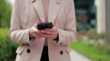 Tanımlanamayan birinin yürümesi ve arka planda siyah çantada akıllı telefon kullanması. İş yerinden gelen mesajlara cevap veren, çok yönlü ceketli girişimci..