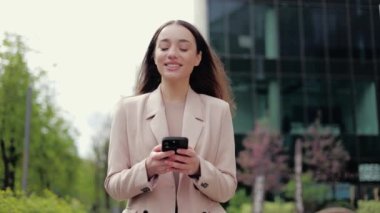 Uzun siyah saçlı, finans bölgesinden geçen ve elindeki elektronik cihaza bakan kendine güvenen bir kadın. Çevrimiçi dijital haritalarda hedef rotayı kontrol eden genç cihaz sahibinin ön görüntüsü.