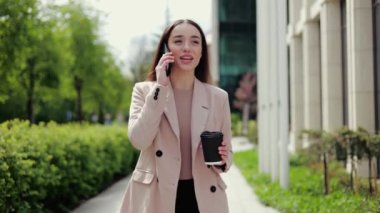Neşeli kadın işe yürürken sabah kahvesini içip sohbet ediyor. Moda kıyafetleri içinde kaygısız bir kadın telefon üzerinden planlarını tartışıyor şehir parkında geziniyor ve etrafa bakınıyor..