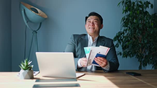 Расслабленный Корейский Бизнесмен Держащий Билеты Паспорт Сидя Освещенном Солнцем Рабочем — стоковое видео