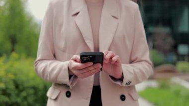 Bilinmeyen beyaz kadın yerleşim alanının yanından geçerken akıllı telefon ekranı kullanıyor. Çağdaş aygıt kullanıcısı posta kutusunu kontrol ediyor ve meslektaşından gelen mesajda gerekli veri aranıyor.