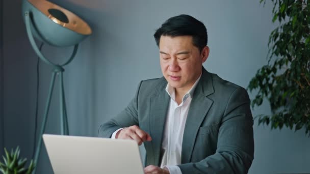 Nieszczęśliwy Japoński Pracownik Masuje Mięśnie Łokcia Podczas Korzystania Przenośnego Laptopa — Wideo stockowe