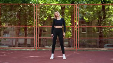 Basketbol sahasında esneyen spor elbiseli bir kadın. Sportif kız antrenmana hazırlanıyor.