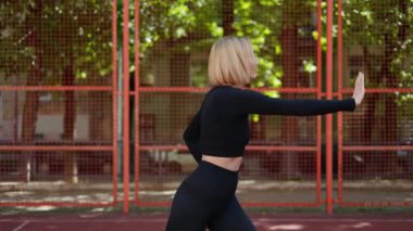 Spor giyim sektöründe formda bir kadın spor sahasında vücudunu esneterek egzersize hazırlanıyor..