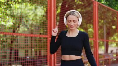 Gülümseyen sporcu kadın şehirde koşarken şarkı listesi müziği eşliğinde dans eder. Fitness, egzersiz ve teknoloji.