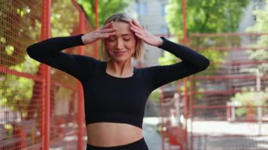 Spor giyim sektöründe mutlu genç bir kadın spor salonunda dans ediyor ve kameraya gülümsüyor.