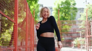 Zinde ve mutlu bir kadın dans eder ve güzel bir yaz gününün tadını çıkarır kırmızı bir çitin yanında..