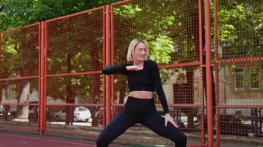 Genç sarışın kadın spor sahasında çalışırken mutlu bir şekilde dans ediyor. Spor rutininin tadını çıkarıyor..