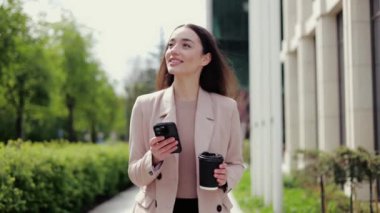 Günışığı caddesinde yürürken modern akıllı telefondan mesaj yazan çekici bir kadın. İşten sonra dinlenen mutlu bir kadın ve eve dönerken sohbet ederken bir fincan kahve içen..