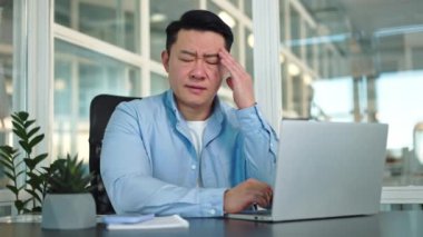 Sağlıksız bir adam yaralı kafasını eliyle tutuyor ve dikkati laptopun ekranından başka yöne çekmek için gözlerini kapıyor. Şirket ofisinde stresli bir iş gününün ardından gergin bir insan....
