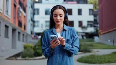 Kulaklıkla müzik dinleyen ve şehirde dans eden tasasız mutlu bir kadın.