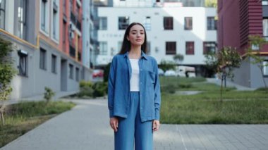 Mavi takım elbiseli kendine güvenen genç bir kadın şehirde kameraya gülümsüyor. İş kadını, şehir hayatı konsepti.