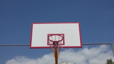 Açık hava maçı sırasında basketbolu potaya doğru fırlatan sporcu adamın eli kapanıyor. Bulutlu mavi gökyüzüne karşı basketbol sahasında eylem. Sporun özü, hobi ve temiz hava üzerine eğlence..