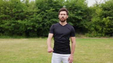 Dışarıda kollarını açan siyah tişörtlü, odaklanmış beyaz bir erkek. Aktif genç sakallı atlet açık hava fitness rejimine başlıyor. Egzersiz ve sağlıklı yaşam tarzına bağlılık.