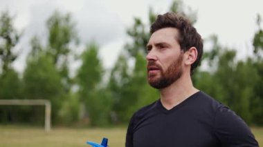 Stadyumdaki futbol maçında çim kaplı yakışıklı erkeklerin susuz kalmaması. Profesyonel hakem devre arasında susuzluğunu gideriyor ve kendinden emin bir ifadeyle ileriye bakıyor..