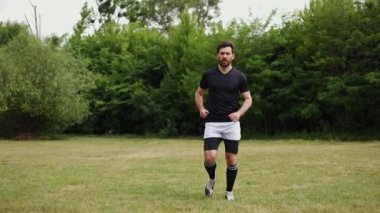Siyah beyaz spor giyim deneyimli bir koşucu çimen tarlasında koşarken travma geçiriyor. Stresli bir adam avuç içini dizine koyar ve eklem durumunu kontrol eder..