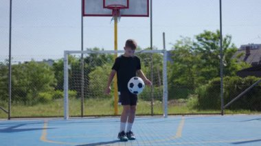 Genç sporcunun ayak vuruşlarıyla futbol topunu havada tutması ve düşüş yörüngesini dengelemesi ön planda. Enerjik çocuk yarışmada başarılı performans için koordinasyon becerisi geliştiriyor.