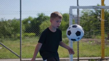 Kısa saçlı, konsantre bir adam topu havaya fırlatıyor ve elinden gelenin en iyisini yapmak için en iyisini yapmaya çalışıyor. Futbol ekipmanları üzerinde hassasiyet ve dikkat tekniği uygulayan bir sporcu..