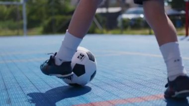 Bilinmeyen çocuğun ayaklarına spor kıyafetler giyip yerel stadyumda siyah beyaz futbol topuyla koşuyor. Genç sporcu profesyonel numaralar yapıyor ve açık havada deneyim kazanıyor..