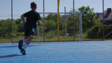 Siyah giysili formalı çocuk topa bacağıyla vururken kapılara nişan alıyor ve kişisel hesabına puan kazanıyor. Yeşil alanda özel evleri olan hırslı bir futbolcu açık alanda eğleniyor..