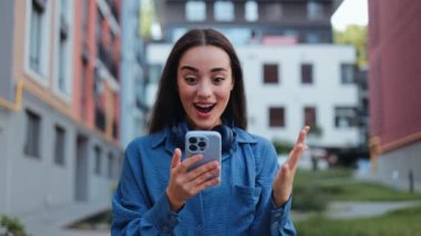 Mutlu genç bayan dışarıda yürürken telefonundan iyi haberler alıyor..