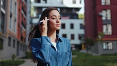 Tasasız genç kadın modern bir şehir ortamında neşeli bir telefon görüşmesi yapıyor..